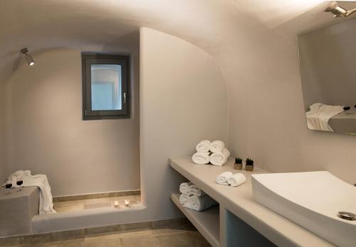 W łazience znajduje się umywalka, lustro i ręczniki. w obiekcie Il Melograno Traditional Cave House w mieście Karterados