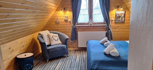 a small room with two beds and a chair at Domki Widokowe Wooden Luxury Chalet in Ząb