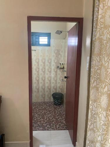 a bathroom with a shower with a toilet and a door at RD's abode in Kozhikode