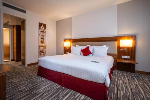 a hotel room with a large bed with red pillows at Mövenpick Hotel Geneva in Geneva