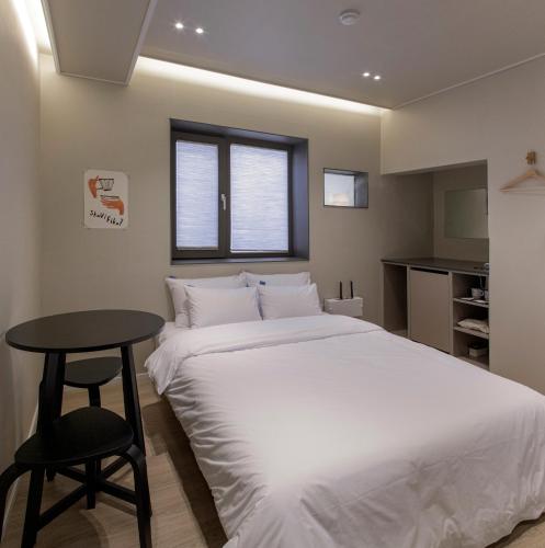 a bedroom with a white bed and a table at Stay Dooroo in Suncheon