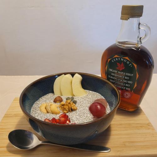 a bowl of rice with fruit and a bottle of syrup at House of Moitelas in Moitelas