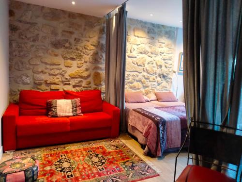 a bedroom with a red couch next to a stone wall at Doma Etxea Donostia-San Sebastian in San Sebastián