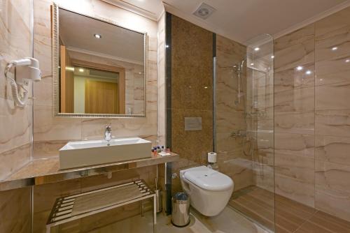 a bathroom with a sink and a toilet and a mirror at İNCEKUM WEST OTEL in Alanya