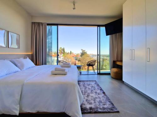 a bedroom with a large white bed and a large window at Aeon Residences - In the heart of Paphos in Paphos City