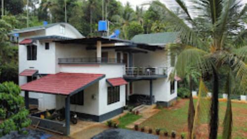 una gran casa blanca con techo rojo en Helen's Villa Kerala, en Kalpetta