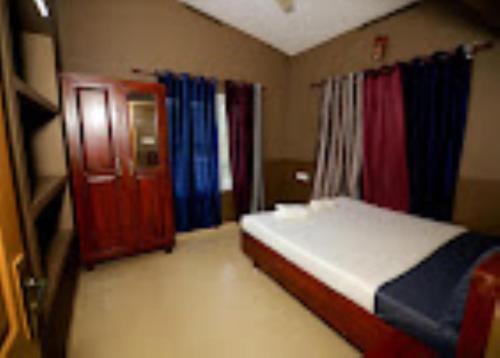 1 dormitorio con 1 cama y una puerta con cortinas en Park Place Holiday Home Kerala, en Vythiri