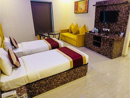 ein Hotelzimmer mit 2 Betten und einem Sofa in der Unterkunft Kusum House in Greater Noida