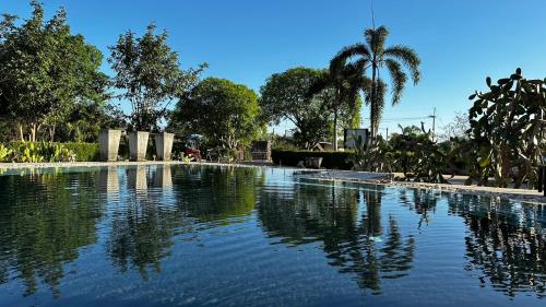 a large pool of water with a palm tree in the background at Hacienda Resort - Mae Phim in Mae Pim