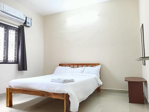 a bedroom with a bed with white sheets and a window at Rose Villa Pondicherry in Puducherry