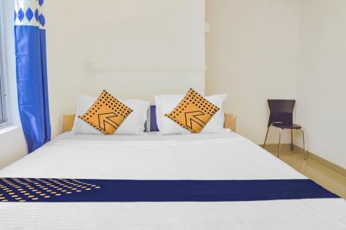 a bedroom with a white bed with pillows and a chair at SPOT ON Nirvaan Guest House in Kāhārpāra