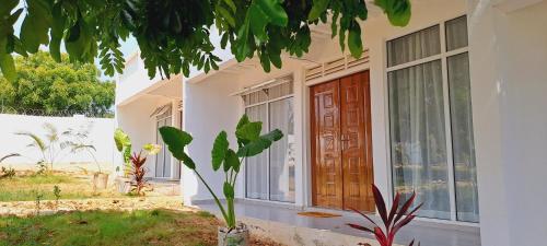 a house with a wooden door and a plant at Cave Diani Holiday Apartments in Diani Beach