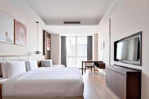 ein Hotelzimmer mit einem Bett und einem Flachbild-TV in der Unterkunft MontClassic Hotel Chongqing in Chongqing