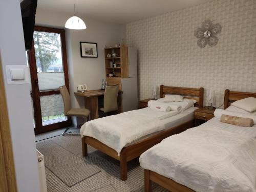 a bedroom with two beds and a desk and a table at Pokoje-Gorlice-Zawodzie in Gorlice