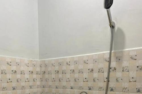a shower head in a bathroom with a tile wall at RedDoorz Syariah near Kantor Bupati Pantai Pandan Sibolga in Halangan