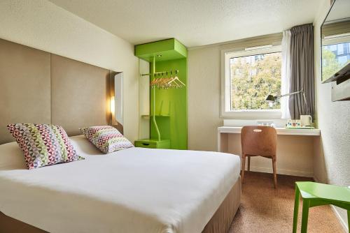 a hotel room with a bed and a desk and a window at Campanile Paris Sud - Porte d'Orléans - Arcueil in Arcueil