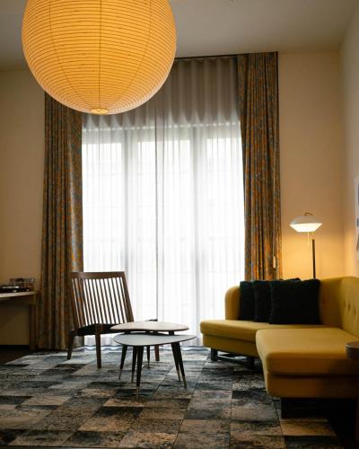 a living room with a yellow couch and a table at Ace Hotel Kyoto in Kyoto