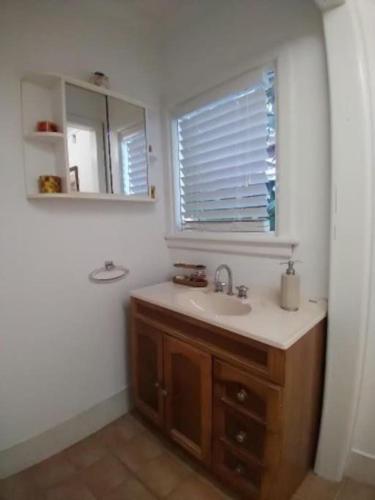 a bathroom with a sink and a mirror at Cosy two bedroom bungalow close to lake and ocean in Berrara