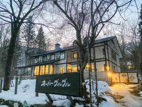 a house in the snow with a sign in front of it at Garden Pension Obergurgl in Hakuba