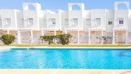 een zwembad voor een wit gebouw bij Garden vistas. Hermoso dúplex con patio, solárium y piscina. in Vera