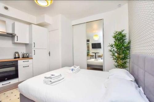 - une chambre blanche avec un grand lit et une salle de bains dans l'établissement Cosy Studio 2P- Gare de l'Est/Paris Center, à Paris