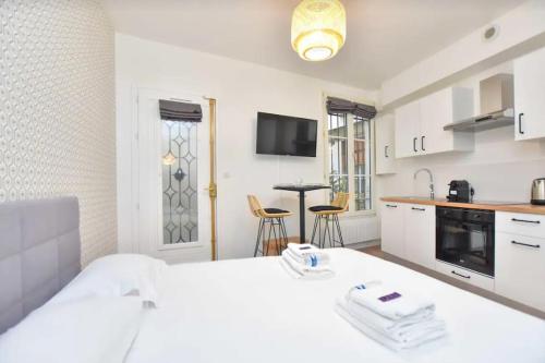 Cet appartement comprend une chambre avec un lit blanc et une cuisine. dans l'établissement Cosy Studio 2P- Gare de l'Est/Paris Center, à Paris