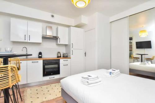 une cuisine avec des armoires blanches et une table dans une pièce dans l'établissement Cosy Studio 2P- Gare de l'Est/Paris Center, à Paris
