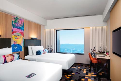 a hotel room with two beds and a large window at Aloft Taipei Beitou in Taipei