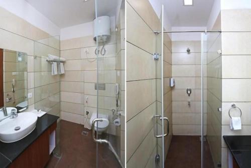 uma casa de banho com uma cabina de duche em vidro e um lavatório. em Hotel Elite Millennium - Near Huda City Centre Gurgaon em Gurgaon