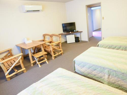 a room with two beds and a table and a television at Ryokan HANAEMI in Otaru