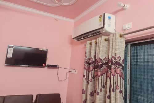 a room with a tv and a curtain at SPOT ON Aaditya Hotel in Patna
