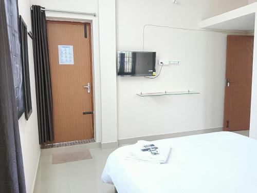 Habitación con cama, puerta y TV. en Rose Villa Pondicherry, en Pondicherry
