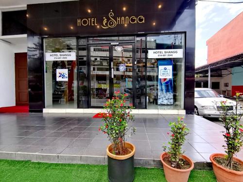 a store front with two potted plants in front of it at Shangg INN in Ipoh