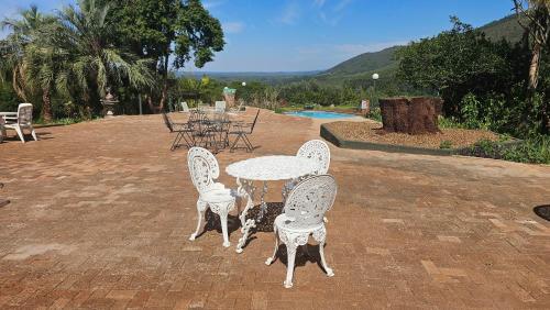 a table and four chairs with a table and a pool at Pecan Farm Guesthouse in Louis Trichardt