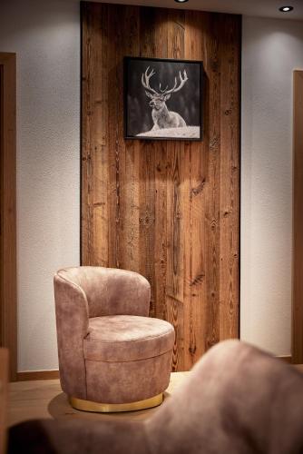 a room with a chair and a deer on a wall at Alpin Residenzen Eichenheim Aurach bei Kitzbühel by Alpina-Holiday in Aurach bei Kitzbuhel