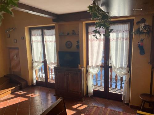 a living room with two doors with curtains and a porch at B&B Borgata 2000 in Borgata Sestriere