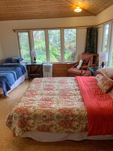 a bedroom with two beds and a chair and windows at Volcano Inn Bed n Breakfast in Volcano