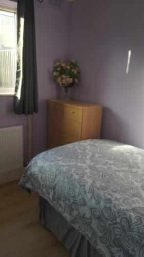 una camera con un letto e un comò con un vaso di fiori di SUNNY SINGLE ROOM in TOOTING a Londra