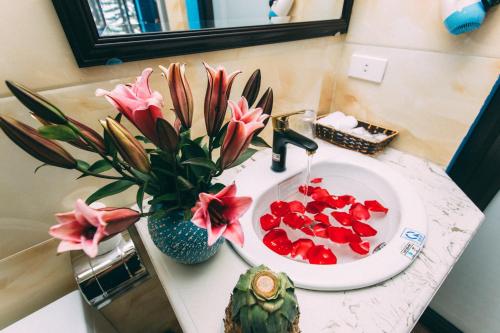 a bathroom sink with a vase of flowers and red fruit at Sapa Nature View Hotel in Sa Pa