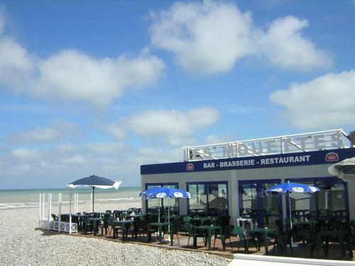 a restaurant on the beach with chairs and umbrellas at "Le JUGUILI" 46m2 en front de Mer - 4 personnes - animaux OK - Entièrement rénové - Haut de gamme - wifi in Mers-les-Bains