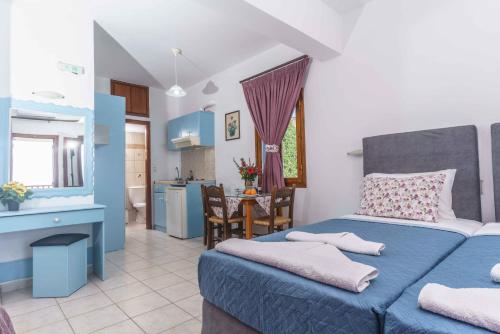 a bedroom with a blue bed and a kitchen at Galini Apartments in Léntas