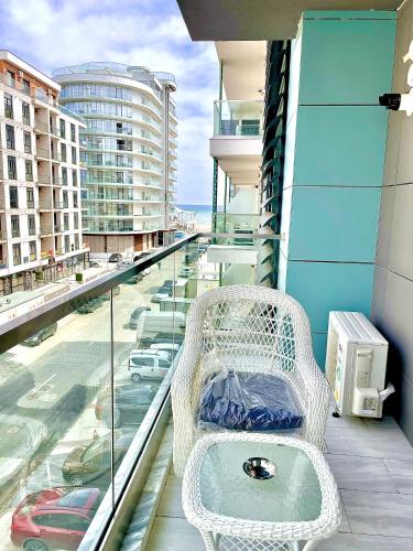 a white rattan bench sitting on a balcony at Summerland Seaview Apartments in Mamaia