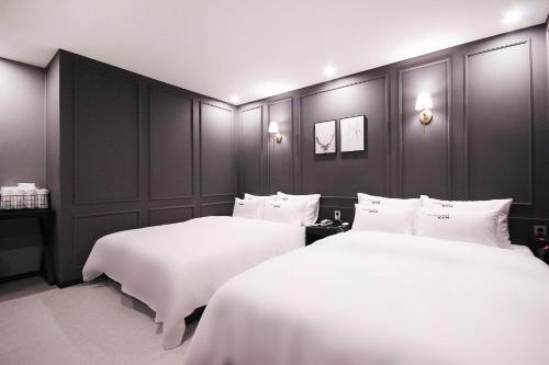 2 Betten in einem Hotelzimmer mit weißer Bettwäsche in der Unterkunft XYM Hotel Mundeok in Pohang