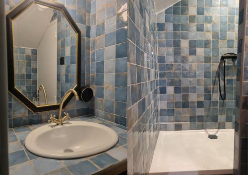 une salle de bain carrelée bleue avec un lavabo et une douche dans l'établissement Escale au Cœur du Mans, entre Gare et Centre, au Mans