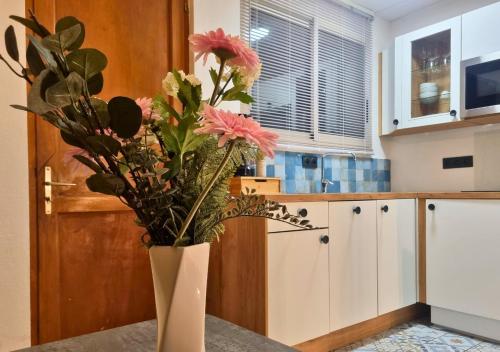 un vase avec des fleurs sur une table dans une cuisine dans l'établissement Escale au Cœur du Mans, entre Gare et Centre, au Mans