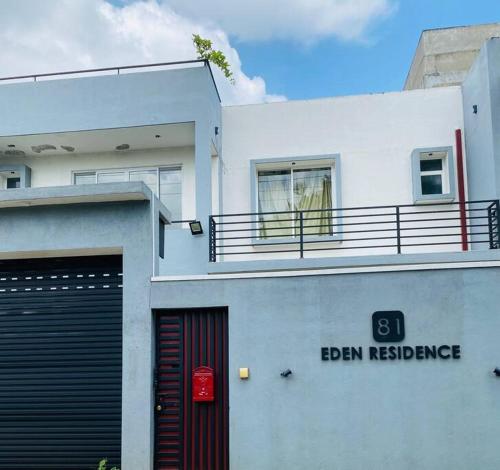 een wit gebouw met een deur en een bord erop bij Eden Residence Home Stay Ja Ela near Airport Highway Exit in Ja-Ela