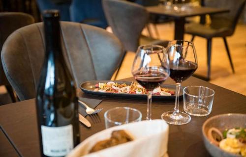 una mesa con dos copas de vino y un plato de comida en Le Grand Som - Chambres au coeur de la Chartreuse en Saint-Pierre-dʼEntremont