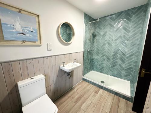 a bathroom with a shower and a toilet and a sink at Harbour Way Cottage by Coast & Country Stays in Seahouses