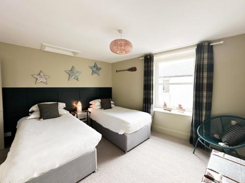 2 camas en una habitación con estrellas en la pared en Harbour Way Cottage, en Seahouses