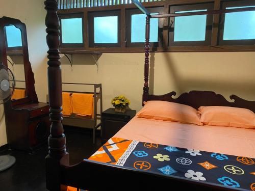 a bedroom with a bed with a wooden frame and windows at Serene Garden Lodge in Ahangama
